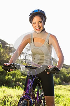 Smiling athletic brunette sitting on mountain bike