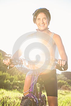 Smiling athletic brunette sitting on mountain bike