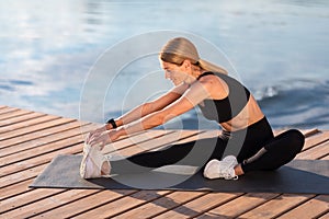 Smiling Athletic Middle Aged Woman Stretching Leg Muscles During Training Outdoors