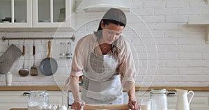 Smiling attractive 30s housewife using rolling pin.