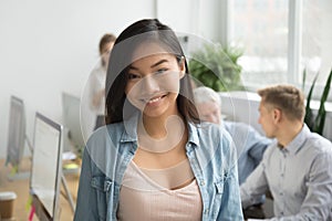 Smiling asian office employee looking at camera working with col