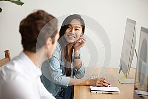 Smiling attractive asian woman talking to male colleague at work