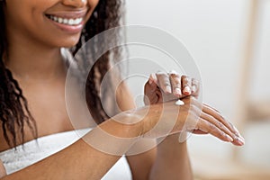 Smiling Attractive Black Female Applying Moisturising Lotion On Hands, Closeup Shot