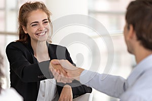 Smiling attractive businesswoman handshaking businessman at meeting negotiation.