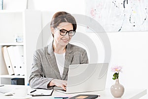 Smiling attractive businesswoman using laptop