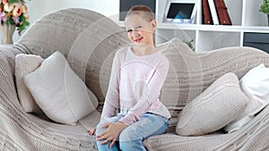 Smiling attractive European female children posing sitting on couch looking camera