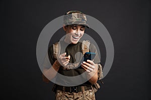 Smiling attractive female soldier using mobile phone