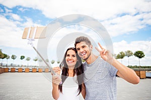Smiling attractive man and woman making selfie on monopod