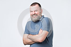 Smiling attractive mature man with beard in blue t-shirt looking directly at the camera