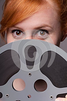 Smiling attractive redhead looking over film reel