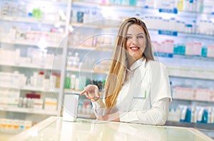 Smiling attractive woman pharmacist displaying a box of tablets or a product in her hands