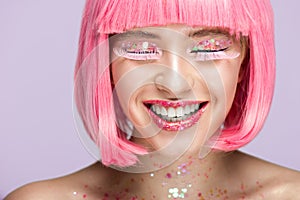 smiling attractive woman with pink hair glittering makeup and long eyelashes