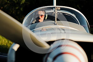 Smiling attractive young man pilot sitting in cabin of small aircraft