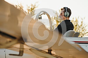 Smiling attractive young man pilot sitting in cabin of small aircraft