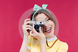 Smiling attractive young woman taking photos using old camera