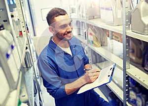 Smiling auto mechanic with clipboard at car shop