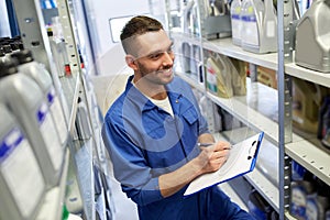 Smiling auto mechanic with clipboard at car shop