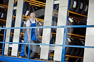 Smiling auto mechanic has sold a car tire