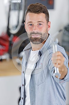 smiling auto mechanic with wrench standing