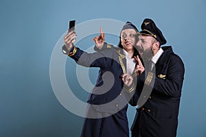 Smiling aviation capitan and air hostess smiling at phone