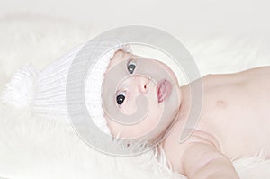 Smiling baby age of 4 months in white knitted hat