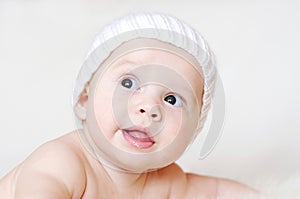 Smiling baby age of 4 months in white knitted hat