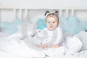 Smiling baby in bed on the bed at home, the concept of a happy loving family and children
