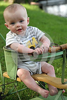 Smiling baby boy in antique stroller waterside