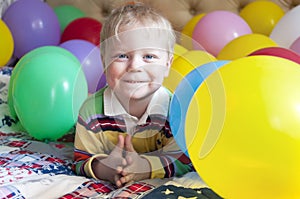 Smiling baby boy with balloons.