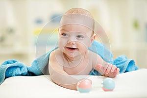 Smiling baby boy in a bathing towel with toy