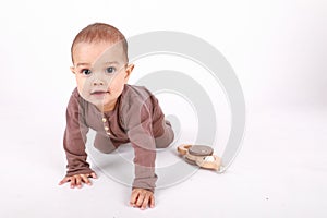 Smiling baby boy crawling by wooden rattle toy