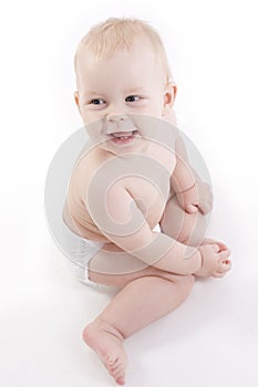 Smiling baby-boy in a diaper sitting on the floor