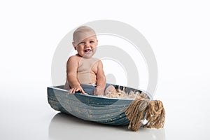 Smiling Baby Boy Sitting in a Tiny, Wooden Boat