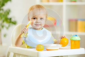 Smiling baby child boy eating itself with spoon photo