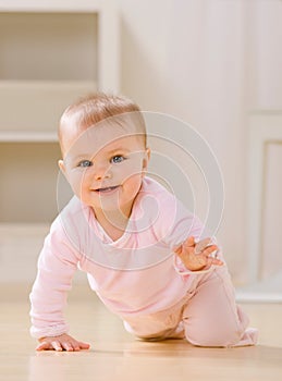 Smiling baby crawling on livingroom floor