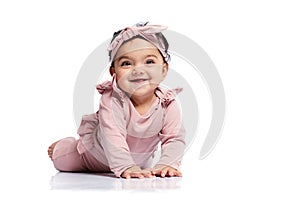 Smiling baby crawling on studio floor.