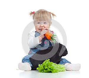 Smiling baby eating a carrot and feeding rabbit