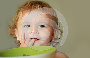 Smiling baby eating food. Healthy nutrition for kids. Funny child face closeup.
