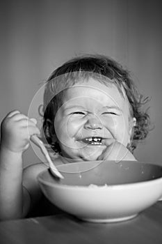 Smiling baby eating food. Launching child with spoon.