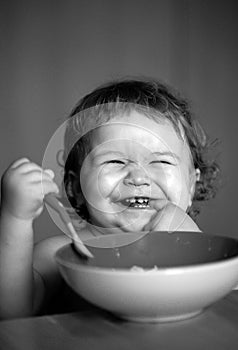 Smiling baby eating food. Launching child with spoon.