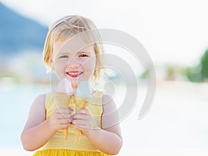 Smiling baby eating two ice cream horns