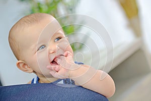 Smiling baby with fingers in mouth