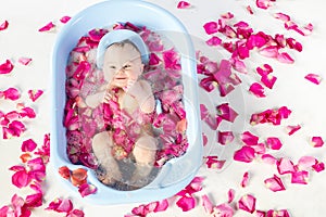 Smiling baby girl bathing in a bathtube with rose