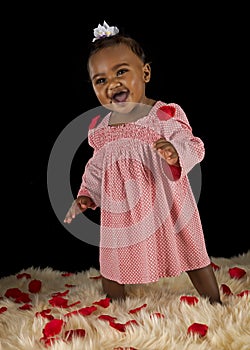 Smiling baby girl covered with rose pedals photo