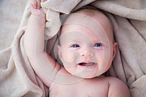 Smiling baby girl lying on a beige towel