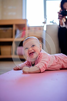 Smiling Baby Girl Lying Down on a Pink Rug