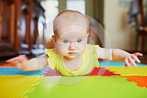 Smiling baby girl lying on play mat