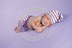 Smiling Baby Girl in a Sleeping Cap and Pants