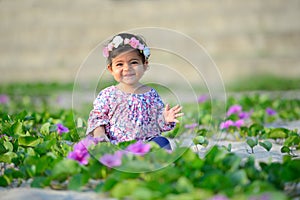 Smiling baby girl wearing colorful suit and flower hat is playin