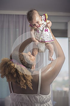 Smiling baby held in the air by her mother
